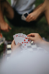 A group of friends enjoying a card game outside on a warm day. The scene captures a sense of relaxation, leisure, and connection in a casual outdoor setting.