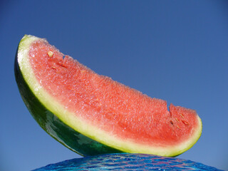 Juicy fresh portion of Watermelon on blue glass plate and sky background. Topics: fruits, natural vitamins, tasty, health, diet, vegetarian, food, meal, deser