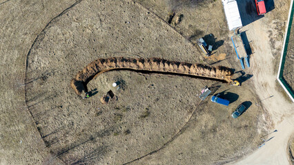 Aerial view of construction workers digging a trench in a field