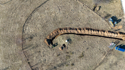 Aerial view of construction workers digging a trench in a field