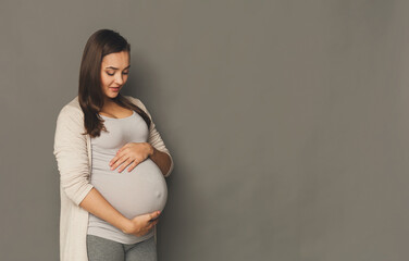 Pensive pregnant woman dreaming about child. Young happy expectant thinking about her baby and enjoying her future life. Motherhood, pregnancy, happiness concept, copy space