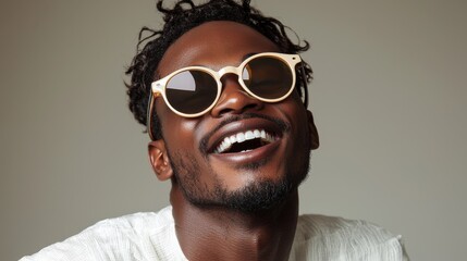 Obraz premium Happy young man smiling while wearing stylish sunglasses against a neutral background indoors