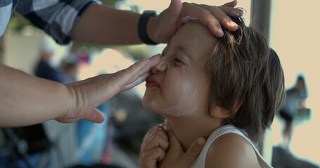 Carefully applying sunscreen to a child's face in slow motion at 800 fps, emphasizing the...