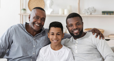 Obraz premium Handsome Senior African Man Embracing His Son And Grandson At Home And Posing To Camera Together, Panorama