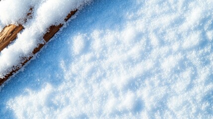 A snow-covered branch lies gently on a vast expanse of untouched snow, glistening in the radiant sunlight of a crisp winter day, creating a serene and tranquil winter landscape