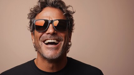Obraz premium A man with curly hair wearing sunglasses smiles warmly against a plain background during a sunny day