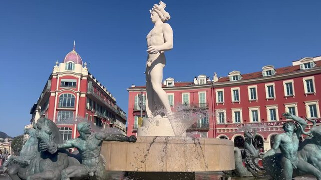 Nice, France - Aug 1, 2024: Fountain The Sun Fountain du Soleil with a marble statue of Apollo timelapse hyperlapse. Buildings in Nice, France. Place Massena Square in Nice, Cote d'Azur, Europe 