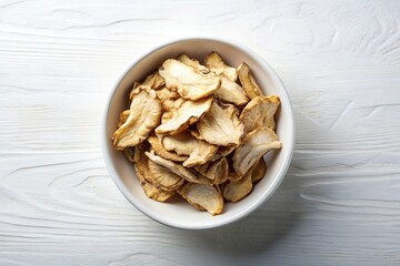 Sliced Angelica root in white bowl on white background, top view