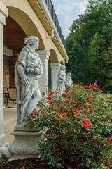 row of statues with roses surrounding them and trees in the background