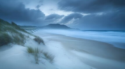 Fototapeta premium A long exposure photograph of the beach. The ocean is calm and blue, with some fog on top