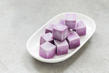 Black Grape ice cream in the form of small cubes. On a plate. Close-up