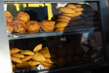 A retail display of Colombian meat empanadas and other traditional and authentic fried snacks for lunch, at a rustic street food market