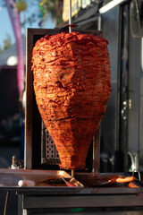 Mexican food stand with a spit of marinated pork, for the preparation of traditional tacos al pastor, roasting on a spit, for an outside lunch