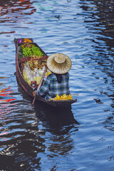 A woman in row boats selling local Thai food at floating market.