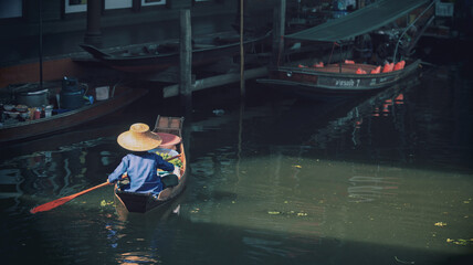 Obraz premium A woman in row boats selling local Thai food at floating market.