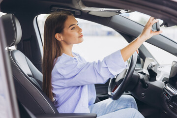 Young Woman Adjusting Rearview Mirror While Driving Modern Car