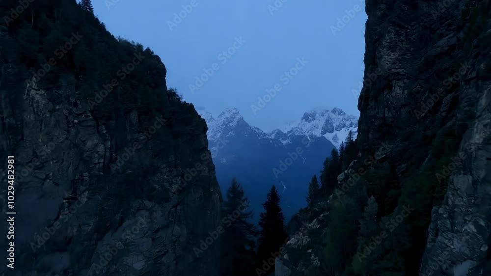 Aufkleber The sun setting, snow capped mountains glow warmly, casting shadows over the valley. Transitioning from light to dark, creating a serene and majestic scene. Twilight sky in the background