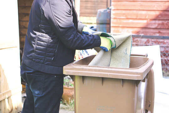 A man puts rubbish into a brown bin