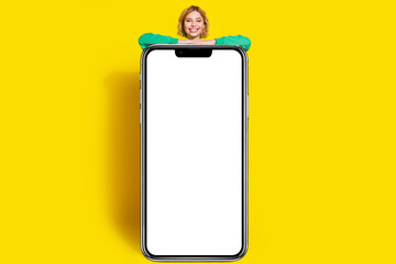 Full length photo of charming positive woman wear green sweatshirt showing modern device empty space isolated yellow color background
