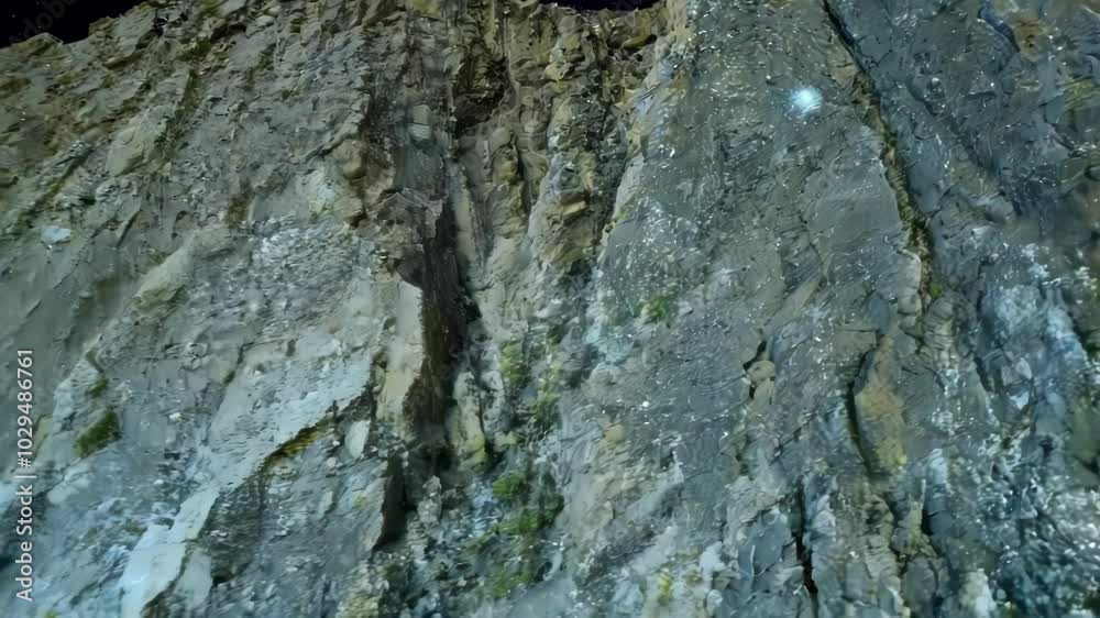 Aufkleber steep cliff face is illuminated by a bright light, showing the rough texture of the rock formations 
