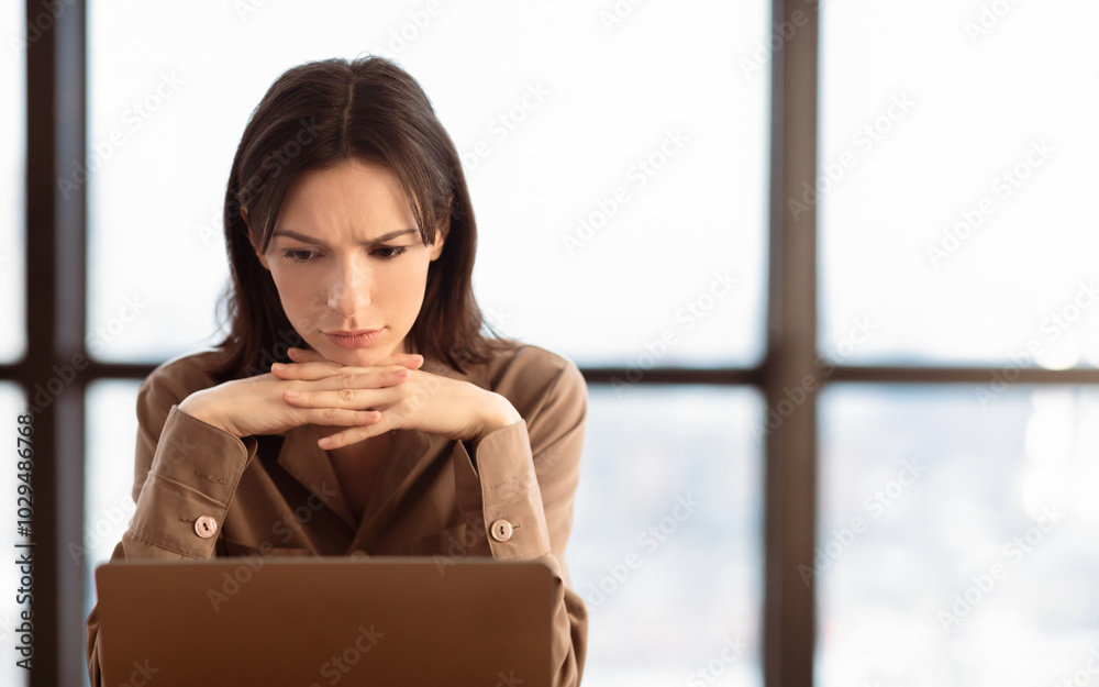 Poster problems at work. confused girl working on laptop, thinking about solution, empty space