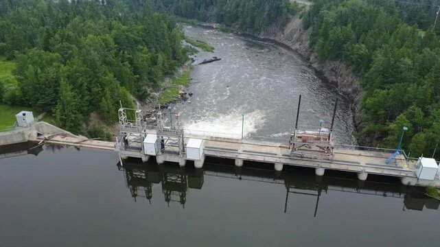Aerial Drone View of Mitis-2 Hydroelectric Dam Wall, Revealing Power Plant Water Outlet, Mitis River Valley, Cliffs, and Dense Forest Landscape