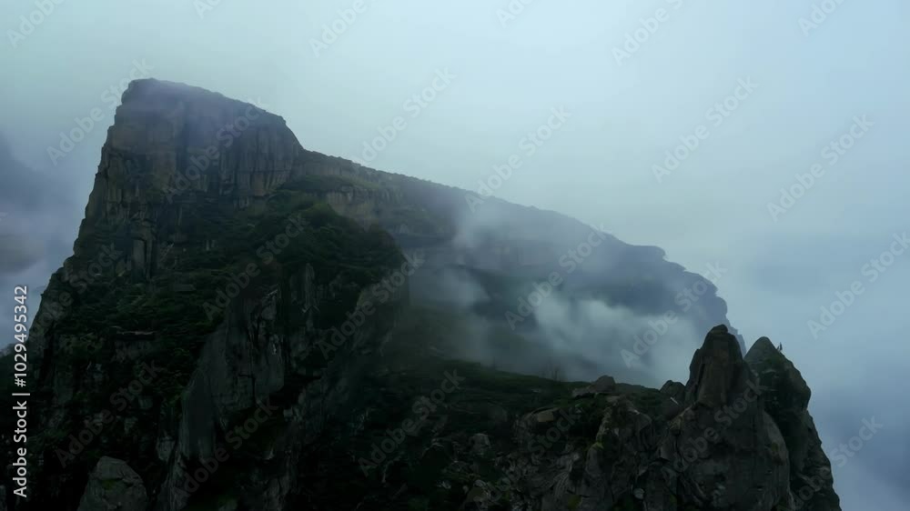 Poster Misty mountain peaks shrouded in fog create a dramatic atmosphere in the wild landscape, with gray clouds adding to the gloomy ambiance