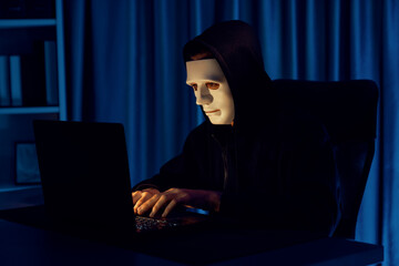 White criminal anonymous mask installing coding password encryption by programming hack, trying to make insecure thorough privacy taking massive database on computer for ransom to company. Pecuniary.