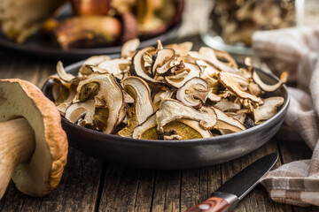 Dried porcini mushrooms. Sliced boletus on plate on wooden table.