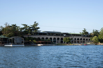 Naklejka premium lake with blue water, and trees and buildings on the shore, Turtle Lake in Tbilisi