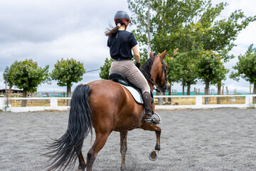girl riding brown horse in equestrian practice