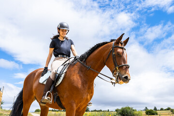 woman riding a brown horse in the countryside