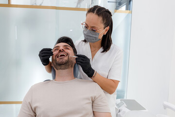 Dentist performing oral examination on a smiling patient in a modern clinic setting