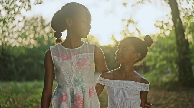 Slow-motion shot of two little girls walking and smiling in forest park in autumn