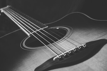 Acoustic guitar on black background, sunbrust body acoustic guitar parts close up,  plucked instrument, shallow depth of field part of a acoustic guitar, guitar chords, playing music, black and white