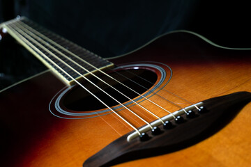 Acoustic guitar on black background, sunbrust body acoustic guitar parts close up,  plucked instrument, shallow depth of field part of a acoustic guitar, guitar chords, playing music
