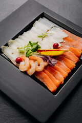 Fresh seafood platter with salmon and shrimp slices, garnished with herbs and lemon for dining