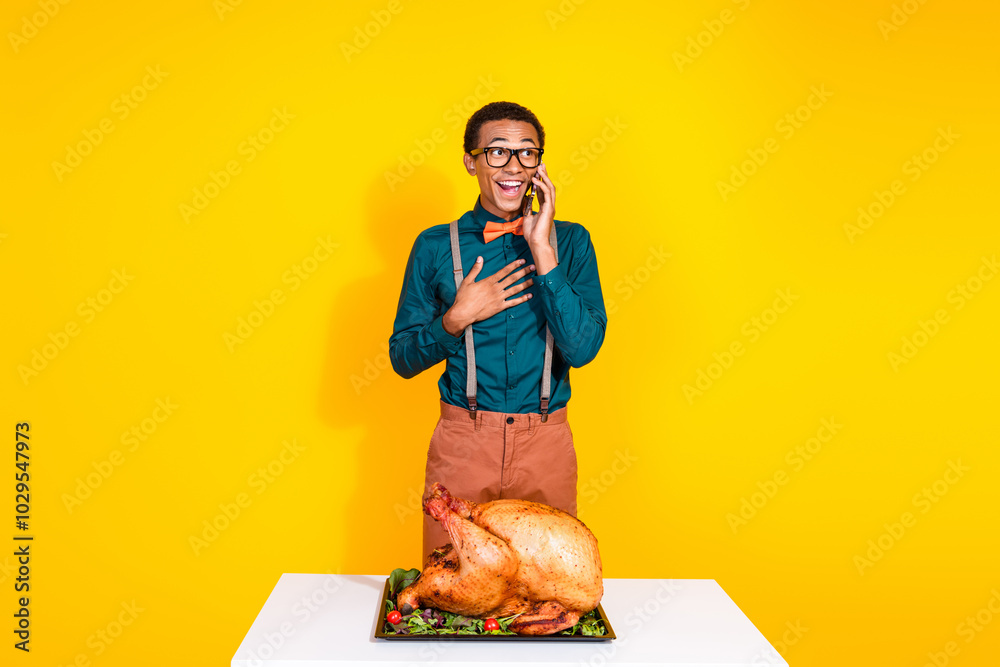 Poster Photo of classy young man communicate phone congratulate thanksgiving roasted turkey isolated on yellow color background