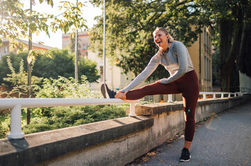 Young sporty woman stretching her legs and smiling before running in the city