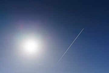 A view straight into the sun, with a plane flying in the background