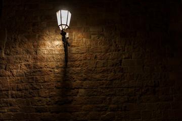 An atmospheric and delicately glowing lamp, illuminating a brick wall.