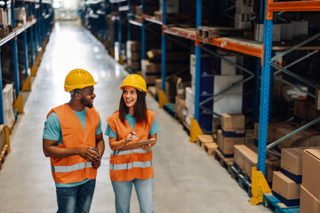 Warehouse workers walking and discussing logistics using digital tablet