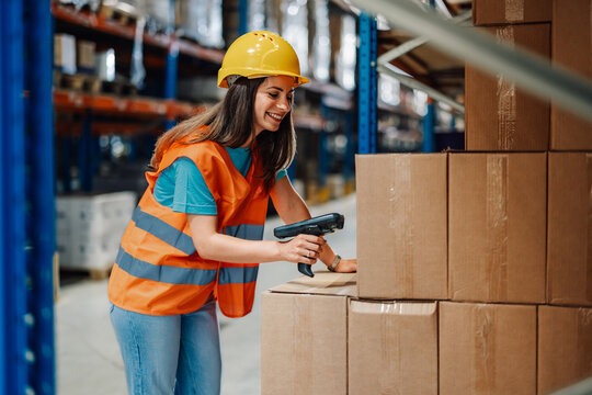 Female warehouse worker scanning barcodes on boxes