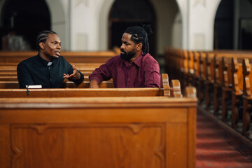 Priest discussing with man on church bench