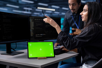 Coworkers using isolated screen device to oversee servers used for managing databases. Colleagues...