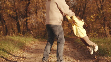 Obraz premium happy family park. father circling little child daughter his arms autumn park. kid with dad dreams becoming pilot. concept childhood dream flight. child spinning with his father forest autumn leaves