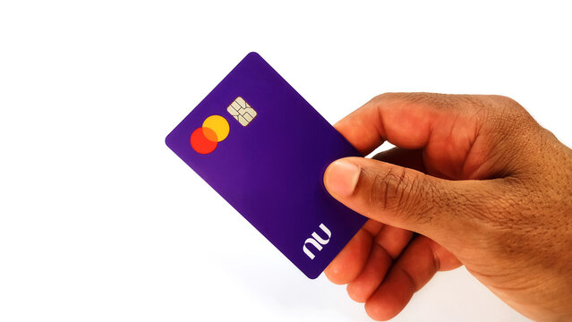 Black male hand and holding Nubank visa credit card on the white background with copy space. Itabira, Brazil, October 08, 2024. 

