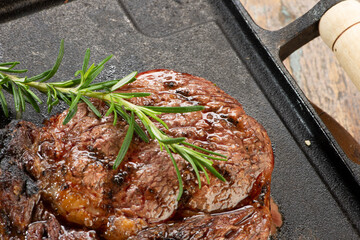 Grilled filet to be served on an iron plate, top view on a wooden table.