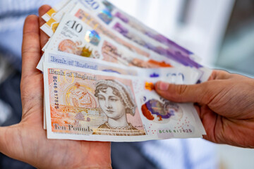 Woman counting Great Britain Pound banknotes, Close-up feminine hands sorting British currency,...