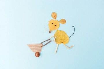 arrangement of pressed dried autumn leaves and twigs on a plain blue background, forming the shape...